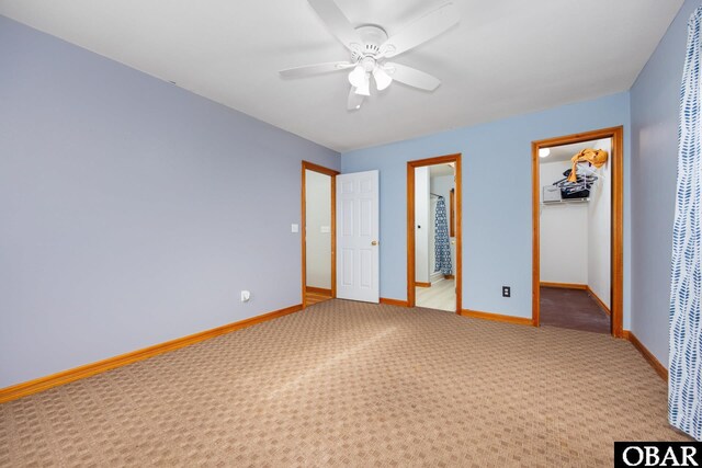 unfurnished bedroom with a walk in closet, a closet, light colored carpet, and baseboards