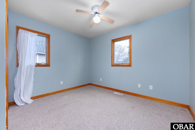 unfurnished room featuring light carpet, visible vents, baseboards, and a ceiling fan