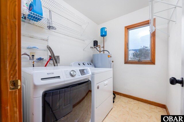 clothes washing area featuring laundry area, independent washer and dryer, electric water heater, and baseboards