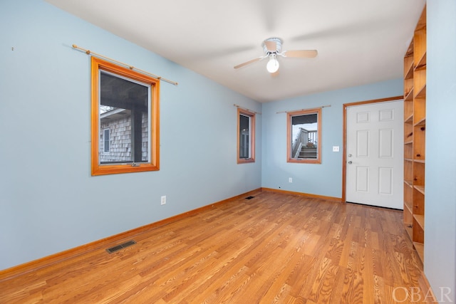 unfurnished room with ceiling fan, light wood-style flooring, visible vents, and baseboards