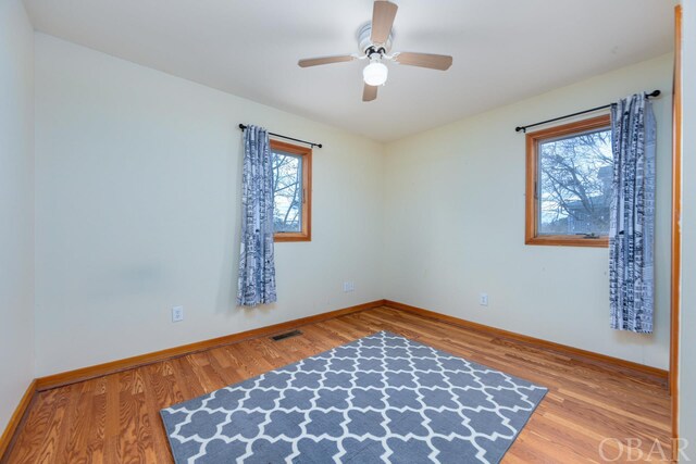 spare room with visible vents, plenty of natural light, and wood finished floors