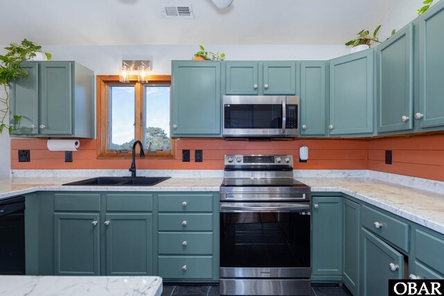 kitchen featuring light stone counters, visible vents, stainless steel appliances, and a sink