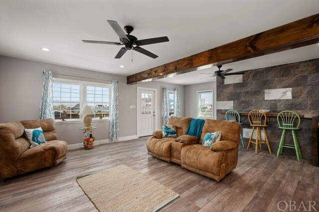 living area with beamed ceiling, a fireplace, plenty of natural light, and wood finished floors