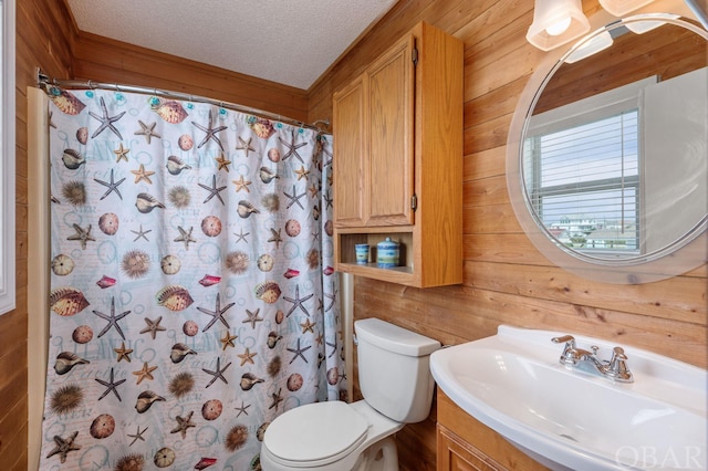 bathroom featuring a shower with shower curtain, toilet, a textured ceiling, vanity, and wood walls