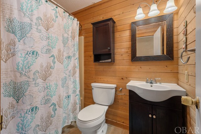 bathroom with toilet, a shower with curtain, vanity, and wooden walls