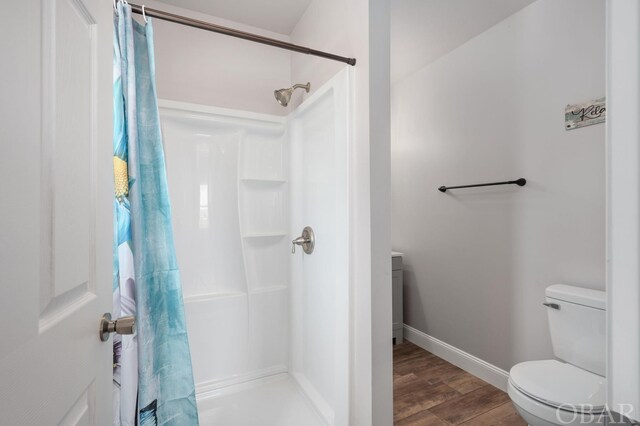 full bath with a stall shower, toilet, baseboards, and wood finished floors