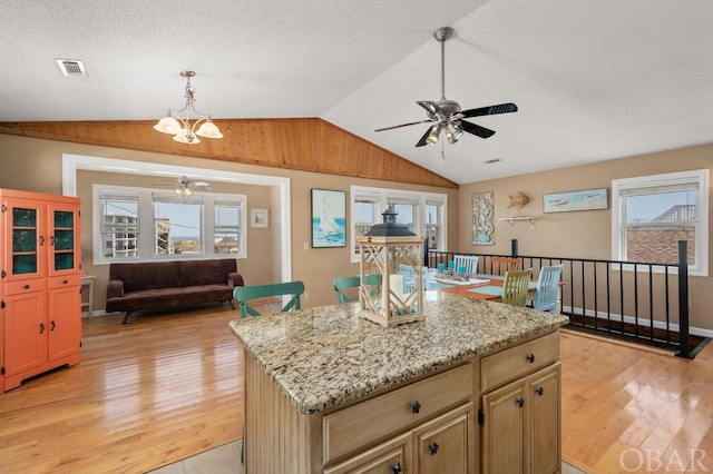 kitchen featuring lofted ceiling, a healthy amount of sunlight, visible vents, and a center island