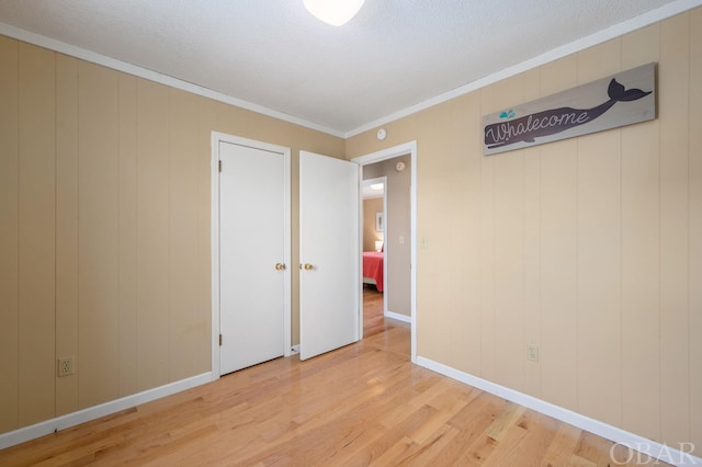 unfurnished bedroom with crown molding, baseboards, and light wood-style floors