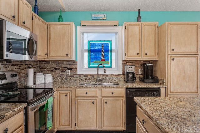 kitchen featuring light stone countertops, appliances with stainless steel finishes, a sink, and light brown cabinetry