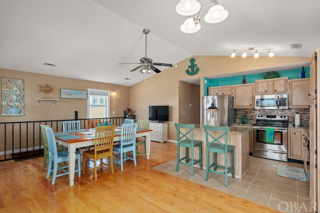 kitchen featuring lofted ceiling, light wood-type flooring, tasteful backsplash, and appliances with stainless steel finishes