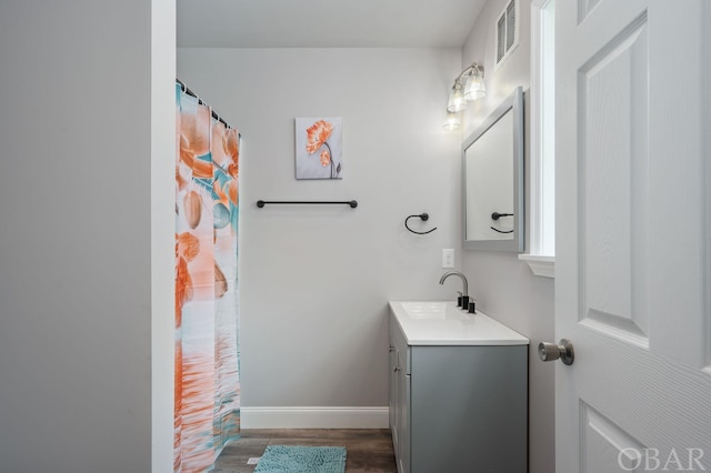 bathroom featuring visible vents, wood finished floors, vanity, and baseboards