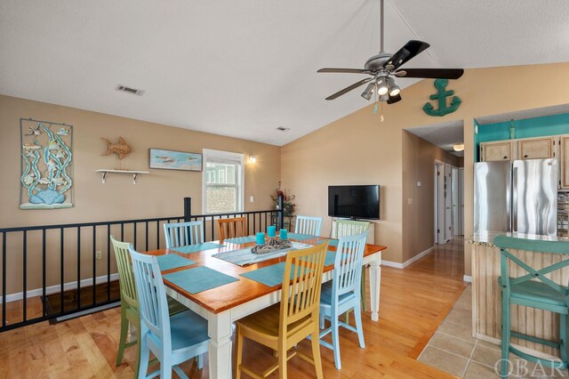 dining room featuring visible vents, baseboards, lofted ceiling, light wood-style flooring, and ceiling fan