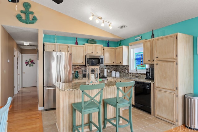 kitchen with light brown cabinets, stainless steel appliances, a kitchen island, and visible vents