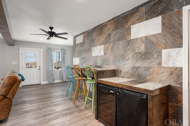 bar featuring a dry bar, beverage cooler, a ceiling fan, wood finished floors, and refrigerator