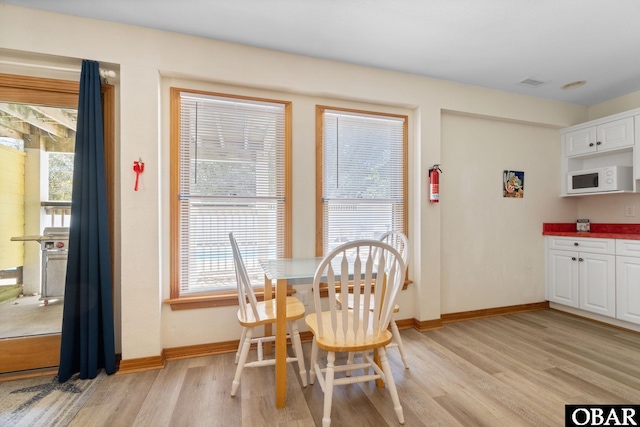 dining area with visible vents, light wood-style flooring, and baseboards