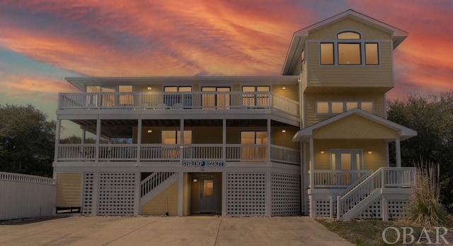 beach home with a carport, concrete driveway, a porch, and stairway