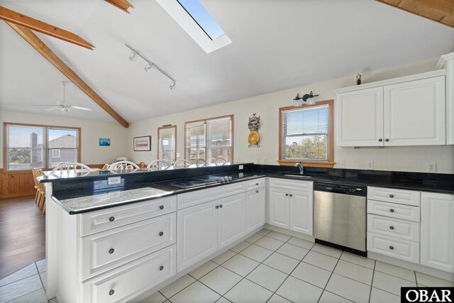 kitchen featuring a peninsula, lofted ceiling with skylight, white cabinetry, and dishwasher