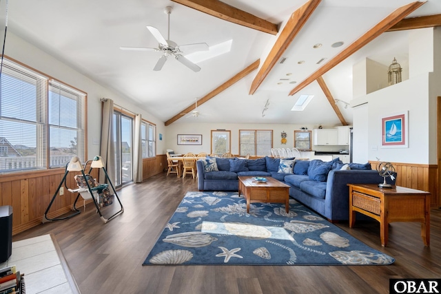 living area featuring a skylight, a wainscoted wall, beamed ceiling, and wooden walls