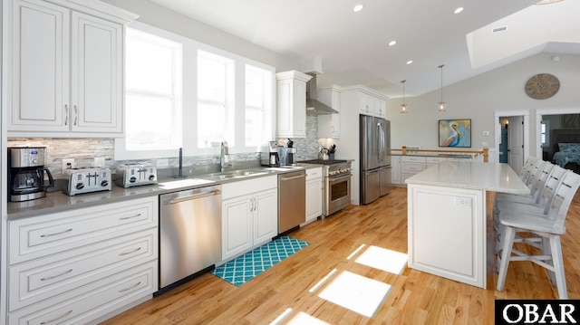 909 Lighthouse Dr Lot # 8, Corolla, NC 27927 - kitchen featuring stainless steel appliances, decorative backsplash, a kitchen island, light wood finished floors, and vaulted ceiling