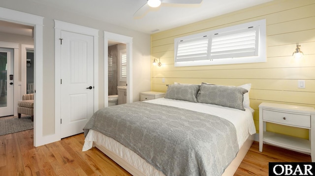 909 Lighthouse Dr Lot # 8, Corolla, NC 27927 - bedroom with light wood-style flooring, wooden walls, ensuite bathroom, and a ceiling fan