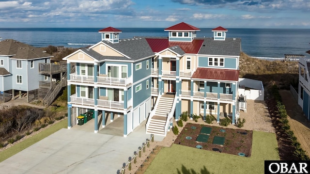 909 Lighthouse Dr Lot # 8, Corolla, NC 27927 - view of front facade with a carport, concrete driveway, a balcony, a water view, and a metal roof