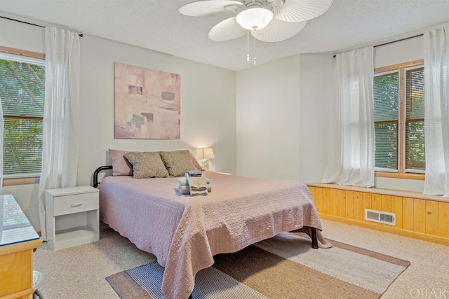 bedroom with a ceiling fan, visible vents, a textured ceiling, and light carpet