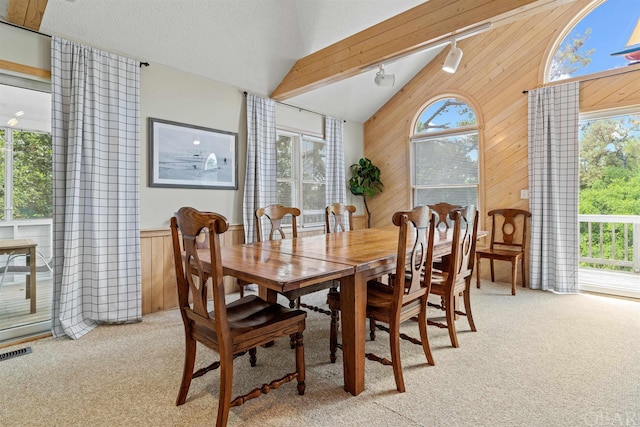 dining area with lofted ceiling, wooden walls, light carpet, and visible vents