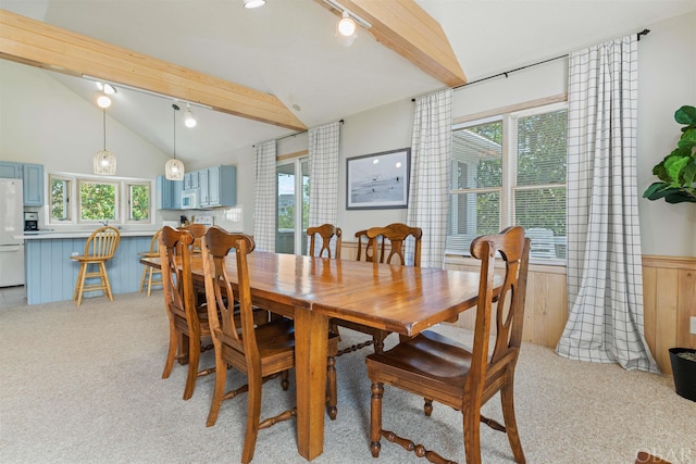 dining space featuring vaulted ceiling with beams, a wainscoted wall, and light colored carpet