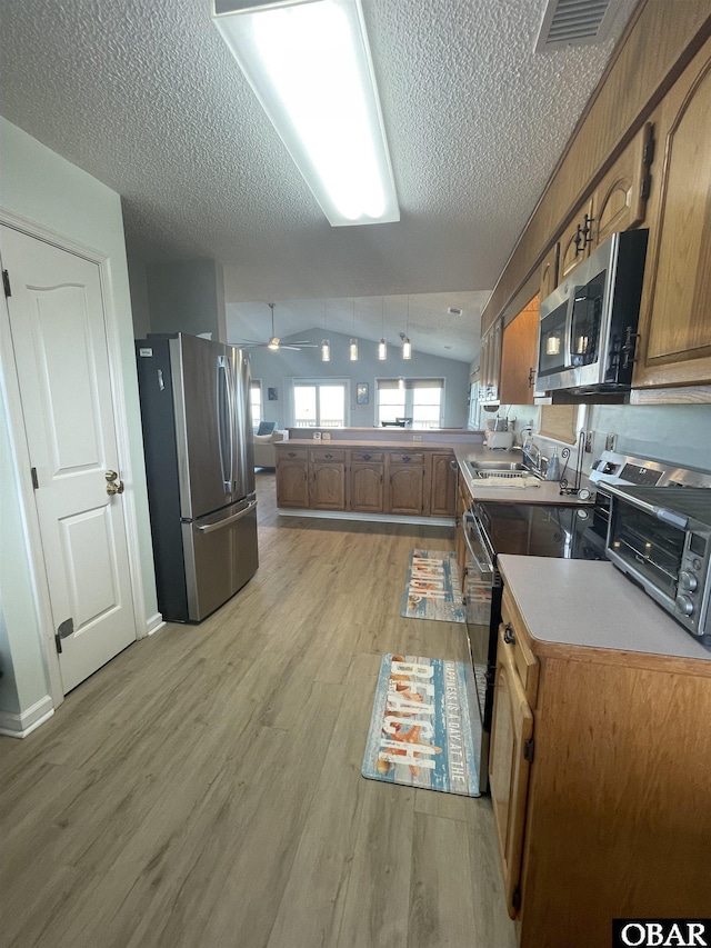 25273 Sea Isle Hills Dr Lot 5-2, Waves, NC 27982 - kitchen featuring appliances with stainless steel finishes, light wood-type flooring, vaulted ceiling, a peninsula, and a textured ceiling