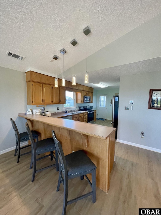 25273 Sea Isle Hills Dr Lot 5-2, Waves, NC 27982 - kitchen with stainless steel appliances, light wood-type flooring, a textured ceiling, a peninsula, and baseboards