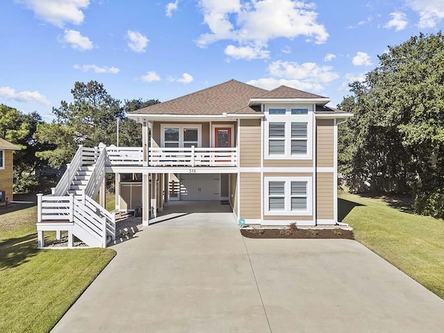 view of front of home featuring roof with shingles, concrete driveway, a carport, a front lawn, and stairs