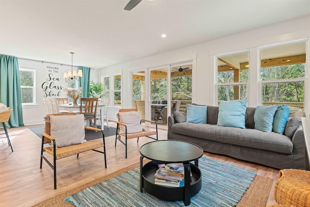 living area with light wood-style floors, recessed lighting, and ceiling fan with notable chandelier