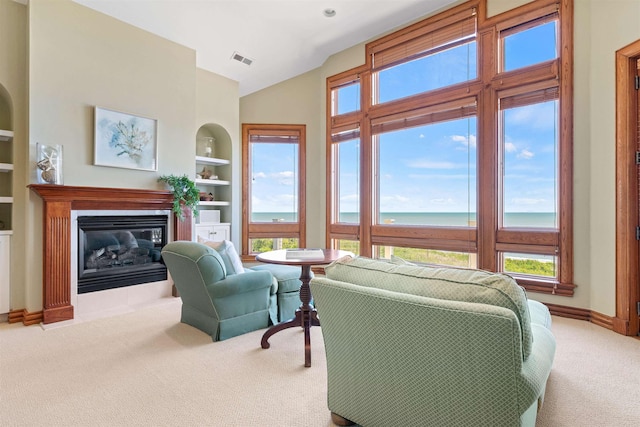 living room with baseboards, visible vents, light colored carpet, a water view, and built in shelves