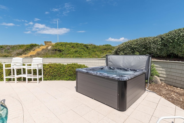 view of patio with a hot tub, stairs, and fence