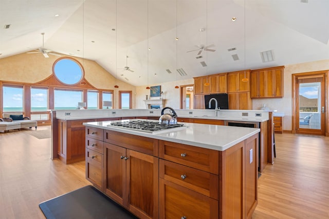 kitchen with stainless steel gas cooktop, a large island, light countertops, open floor plan, and a peninsula