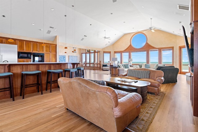 living area with a water view, ceiling fan, visible vents, and light wood finished floors