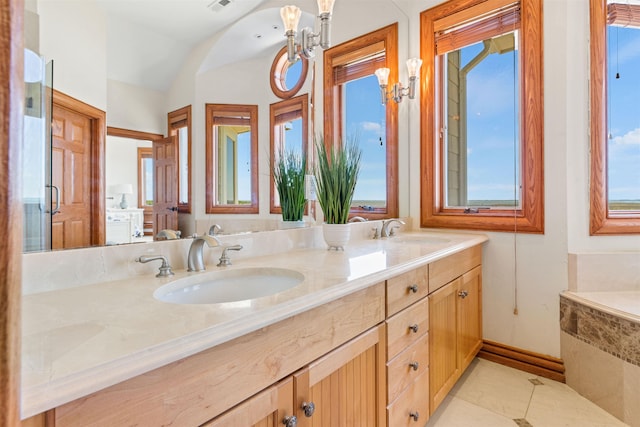 full bath featuring a notable chandelier, double vanity, a sink, and tile patterned floors