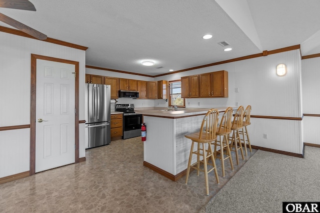 50096 Freebooter Ct Lot 178, Frisco, NC 27936 - kitchen featuring light countertops, appliances with stainless steel finishes, brown cabinetry, a peninsula, and a kitchen bar