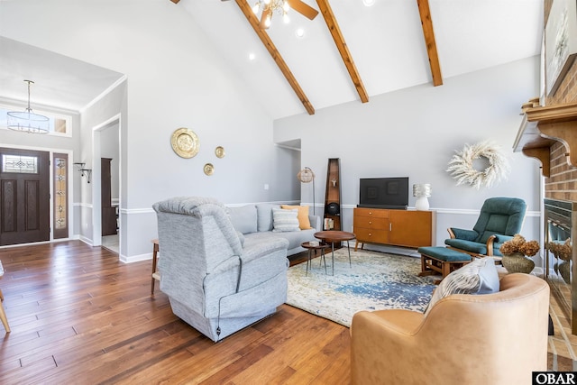 living area with high vaulted ceiling, baseboards, beam ceiling, ceiling fan with notable chandelier, and wood-type flooring