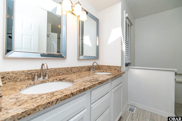 bathroom with double vanity, a sink, baseboards, and wood finished floors
