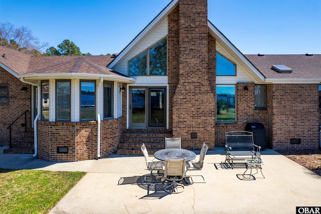 rear view of property featuring entry steps, a chimney, crawl space, brick siding, and a patio area