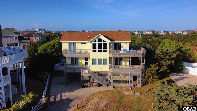back of property featuring stairway, concrete driveway, a balcony, and a residential view