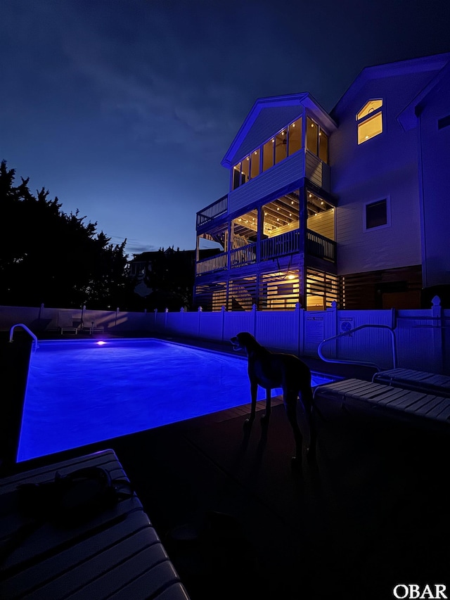 pool at twilight with a fenced in pool and fence