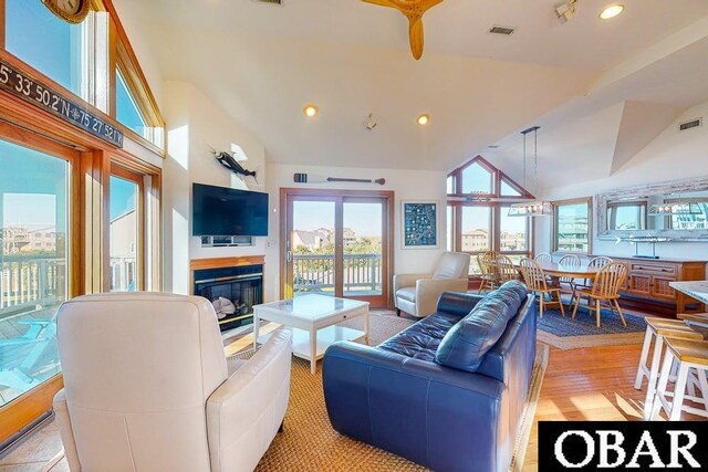 living room with visible vents, recessed lighting, high vaulted ceiling, and a glass covered fireplace