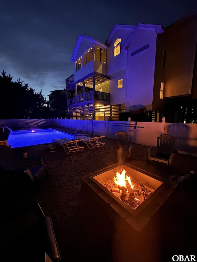 pool at twilight featuring a fire pit, fence, and a fenced in pool