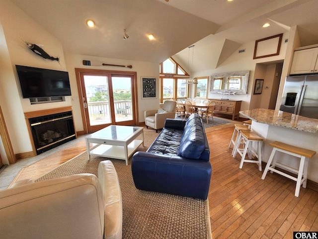 living room featuring lofted ceiling, a healthy amount of sunlight, and light wood-type flooring