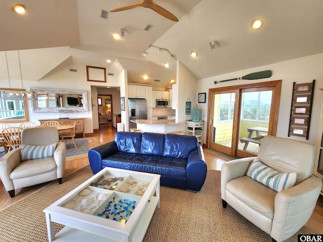living area featuring visible vents, light wood-type flooring, a ceiling fan, and vaulted ceiling