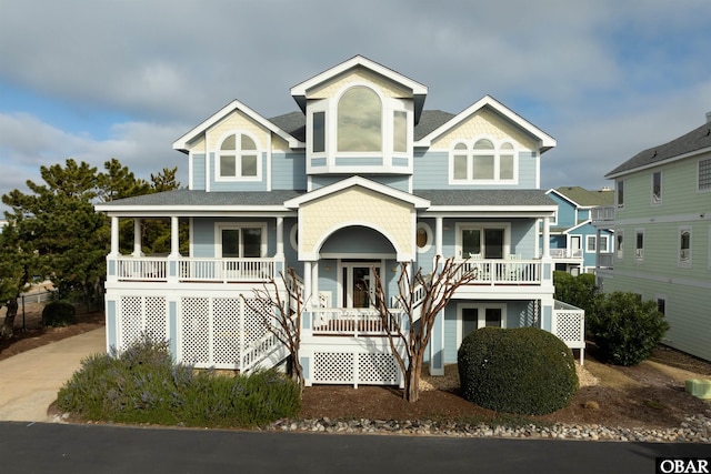 view of front facade with concrete driveway, a porch, and a shingled roof