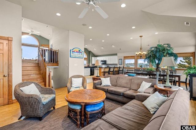 living area featuring stairway, a healthy amount of sunlight, vaulted ceiling, and light wood-style flooring