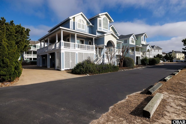 view of front of property with driveway, covered porch, a residential view, and stairway